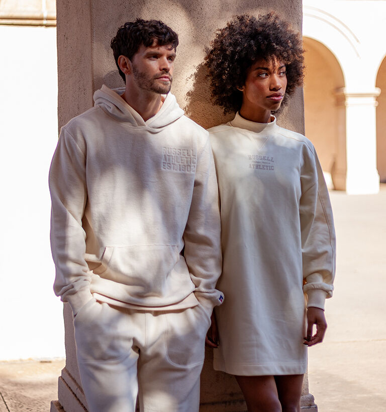 Male model in a cream hoodie and female model in a cream colored dress. Male model in a cream hoodie and female model in a cream colored dress.