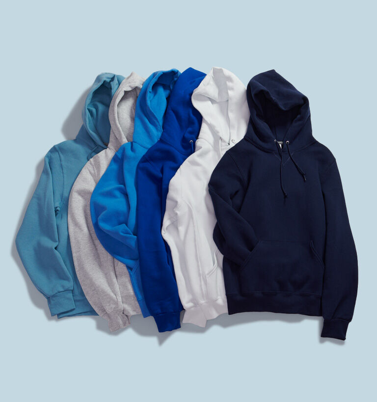 Lay flat image of Russell Athletic pull over hoodies on a blue background. Lay flat image of Russell Athletic pull over hoodies on a blue background.