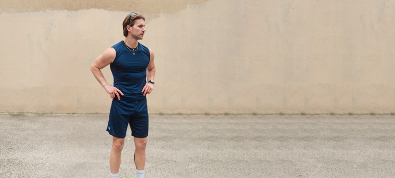 Male model wearing blue coolcore compression muscle shirt and performance shorts standing outside Male model wearing blue coolcore compression muscle shirt and performance shorts standing outside