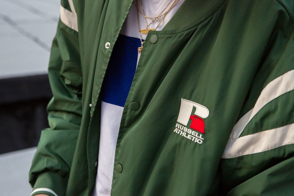 Closeup picture of a person wearing a Russell Athletic bomber jacket.