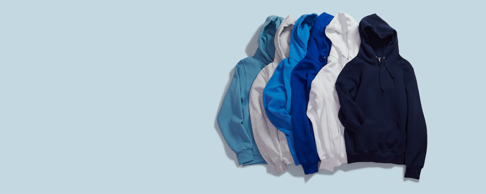 Lay flat image of Russell Athletic pull over hoodies on a blue background.