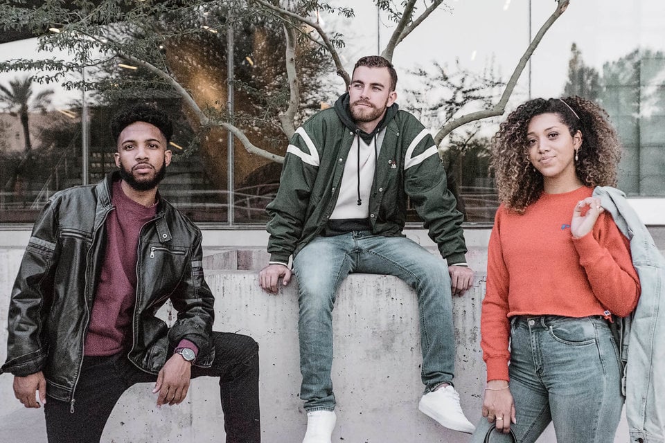 2 men and one woman posing wearing Russell Athletic clothing.